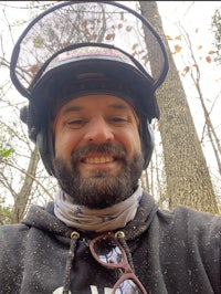 a man wearing a helmet and sunglasses in the woods